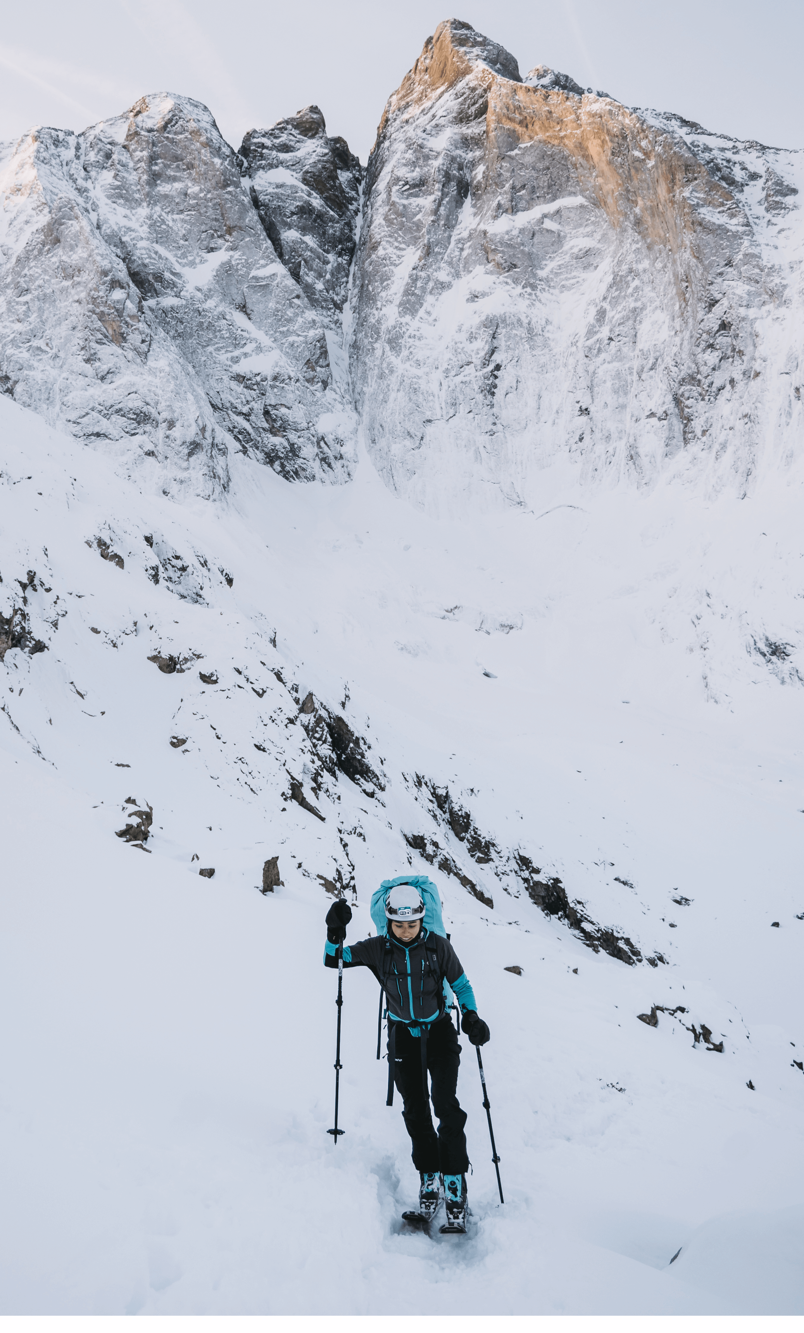 A woman skiing uphill, surrounded by beautiful scenery